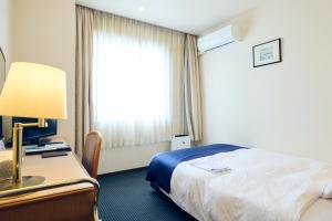 a hotel room with a bed and a desk and a window at Hotel Kumamoto Terrsa in Kumamoto