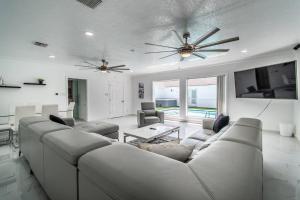 a living room with a large couch and a tv at Poolside Opulence Tennis and HotTub in Corpus Christi