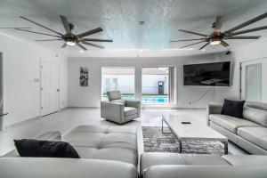 a living room with a couch and two fans at Poolside Opulence Tennis and HotTub in Corpus Christi