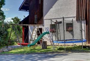 a playground in front of a house with a slide at Ferienhof Landhaus Guglhupf in Sankt Oswald