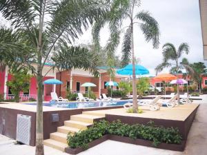 a resort with a swimming pool with chairs and palm trees at At night Airport Resort in Patong Beach