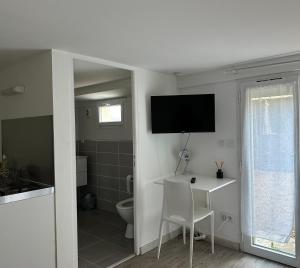 a bathroom with a table and a television on the wall at Studio calme et indépendant proche Tours in Fondettes