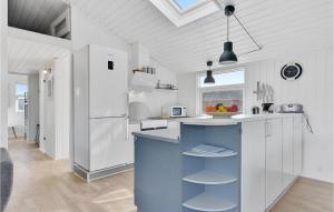 a kitchen with white cabinets and a blue island at Holiday Home As Strandby Juelsminde X in Sønderby