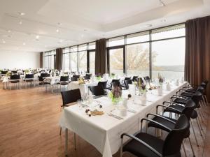 einen großen Bankettsaal mit weißen Tischen und Stühlen in der Unterkunft Panorama Hotel Aschberg in Ascheffel