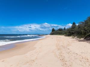 a beach with footprints in the sand and the ocean at Four Pines Shelly Beach Retreat in Caloundra