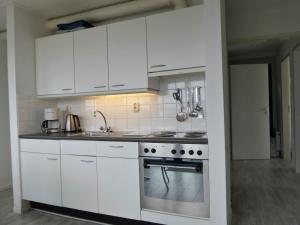 a kitchen with white cabinets and a stove at Ferienhaus Jasmijn mit Garten und Terrasse in Anjum