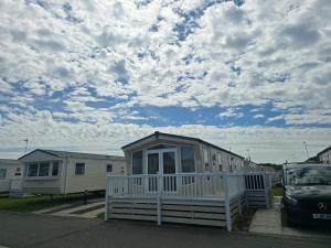 a small house with a porch in a parking lot at Modern caravan Robin Hood Rhyl in Rhyl