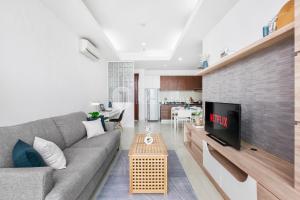 a living room with a gray couch and a tv at Sattva by Kozystay - Kuningan in Jakarta
