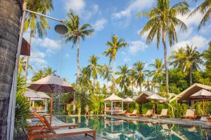 a pool at the resort with chairs and umbrellas at Gili Tenda in Gili Trawangan