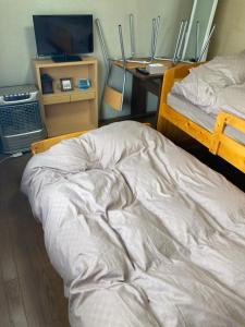 an unmade bed in a room with a television at Home Yasuda in Otaru