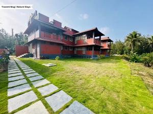 a house with a large yard in front of it at Pepper Corn Retreat By Travent Mug in Sakleshpur