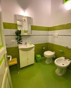 zielono-biała łazienka z umywalką i toaletą w obiekcie Appartamento Casa Trento w mieście Castellammare del Golfo