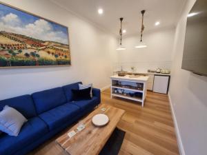a living room with a blue couch and a table at Winemakers Cottage at Treetops Red Hill in Red Hill