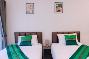 two beds in a room with green and white pillows at มนต์จันทรา เฮ้าส์ in Khlong Lan