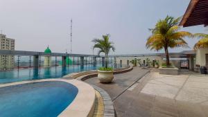 una piscina en la parte superior de un edificio con palmeras en Modern and Homey 2BR at MT Haryono Square Apartment By Travelio, en Yakarta