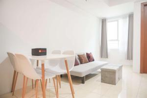 sala de estar blanca con mesa y sofá en Modern and Homey 2BR at MT Haryono Square Apartment By Travelio, en Yakarta