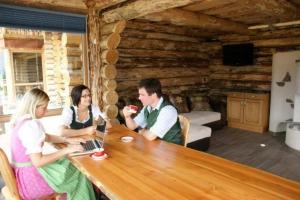 eine Gruppe von Personen, die an einem Tisch mit einem Laptop sitzen in der Unterkunft Exklusives Chalet am Waldesrand mit Traumaussicht, eigener Sauna, Kamin und Wintergarten in Tamsweg