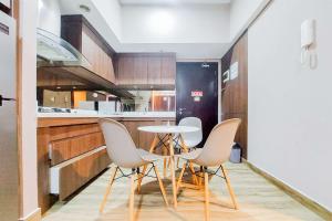 a kitchen with a table and chairs and a refrigerator at Homey and Modern 2BR at Casa de Parco Apartment By Travelio in Tangerang