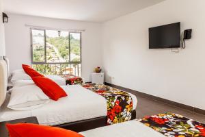 a bedroom with two beds and a flat screen tv at Hotel Casa Suite Curiti in Curití