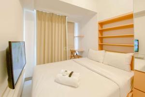 ein Schlafzimmer mit einem weißen Bett und einem Fernseher in der Unterkunft Cozy Studio Apartment Tokyo Riverside PIK 2 By Travelio in Rawalembang