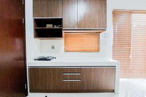 a kitchen with a white counter and wooden cabinets at Comfy and Modern Look 2BR Asatti Apartment By Travelio in Tangerang
