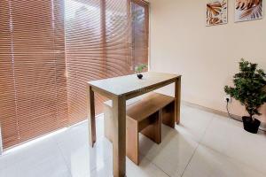 a wooden table in a room with a window at Comfy and Modern Look 2BR Asatti Apartment By Travelio in Tangerang +4 photos