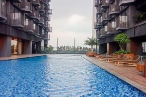 a swimming pool in the middle of two apartment buildings at Enjoy Living 2BR Apartment at Carstensz Residence By Travelio in Kampung Sawah