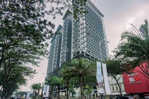 a tall building with palm trees in front of it at Enjoy Living 2BR Apartment at Carstensz Residence By Travelio in Kampung Sawah