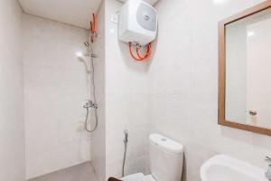 a bathroom with a shower and a toilet and a sink at Good and Homey 2BR at Parkland Avenue Apartment By Travelio in Tangerang +6 photos