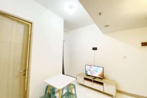 a room with a tv and a table and chairs at Comfortable 2BR at Tokyo Riverside PIK 2 Apartment By Travelio in Rawalembang