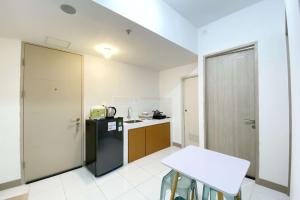 a small kitchen with a black refrigerator and a table at Comfortable 2BR at Tokyo Riverside PIK 2 Apartment By Travelio in Rawalembang