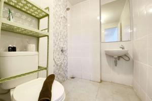 a bathroom with a toilet and a sink at Comfortable 2BR at Tokyo Riverside PIK 2 Apartment By Travelio in Rawalembang