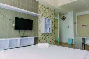 a room with a flat screen tv on a brick wall at Cozy Living Studio Apartment Tree Park City BSD By Travelio in Tangerang