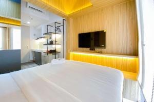 a bedroom with a white bed and a flat screen tv at Comfortable Studio Apartment at Tokyo Riverside PIK 2 By Travelio in Rawalembang