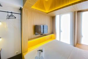 a bedroom with a bed with a tv on the wall at Comfortable Studio Apartment at Tokyo Riverside PIK 2 By Travelio in Rawalembang