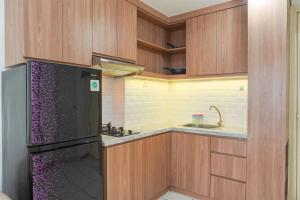 a kitchen with a black refrigerator and a sink at Good Deal and Cozy 2BR Apartment M-Town Residence near Mall By Travelio in Tangerang
