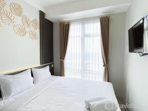 a bedroom with a white bed and a window at Comfort Stay 1BR at Vasanta Innopark Apartment By Travelio in Cikarang