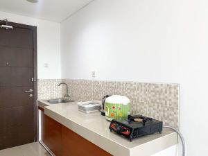 a kitchen with a counter with a toaster and a sink at Cozy and Enjoy Living Studio Enviro Apartment By Travelio in Cikarang