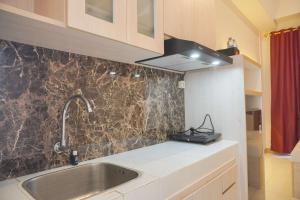 a kitchen with a sink and a stove at Minimalist and Comfy Studio at Tokyo Riverside PIK 2 Apartment By Travelio in Rawalembang