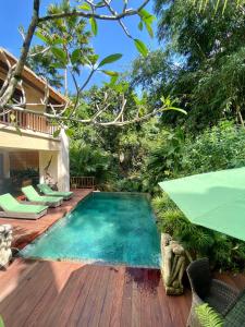 a swimming pool on a wooden deck next to a house at Villa Purnamasari in Ubud