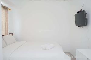 a bedroom with a bed and a tv on the wall at New and Simply Studio at Urbantown Serpong Apartment By Travelio in Tangerang