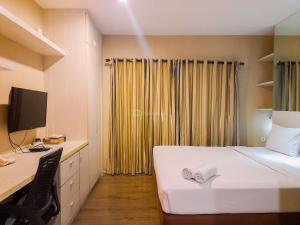 ein Schlafzimmer mit einem Bett und einem Schreibtisch mit einem Computer in der Unterkunft Modern and Cozy Studio at Student Park Apartment By Travelio in Seturan + 4 Fotos