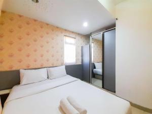ein Schlafzimmer mit einem weißen Bett und einem Spiegel in der Unterkunft Homey and Warm 1BR at Student Castle Yogyakarta Apartment By Travelio in Seturan + 17 Fotos