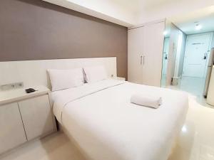 a white bedroom with a large bed and a bathroom at Good Choice and Modern Studio Marquis de Lafayette Apartment By Travelio in Semarang +6 photos