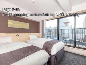 two beds in a hotel room with a balcony at Hotel GOCO stay Kyoto Shijo Kawaramachi in Kyoto