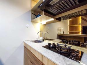 スマランにあるFancy and Nice 1BR with Extra Room at Amartha View Apartment By Travelioのシンクとコンロのあるキッチン トップオーブン
