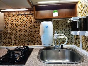 a kitchen sink with a mixer on top of it at Comfort and Strategic 2BR Apartment at Vida View Makassar By Travelio in Pampang +22 photos
