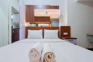 PampangにあるScenic Studio Apartment at Vida View Makassar By Travelioのタオルが敷かれた白いベッドのある寝室 +4枚の写真