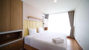 a bedroom with a large white bed with a window at Best Location and Strategic 2BR at Praxis Apartment By Travelio in Surabaya