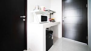 a room with a counter with a microwave and a door at Well Furnished and Homey Studio (No Kitchen) Apartment at Suncity Residence By Travelio in Sidoarjo